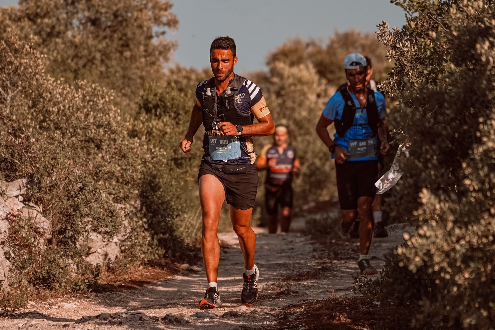 Trois coureurs progressent en autonomie sur un sentier de trail exigeant