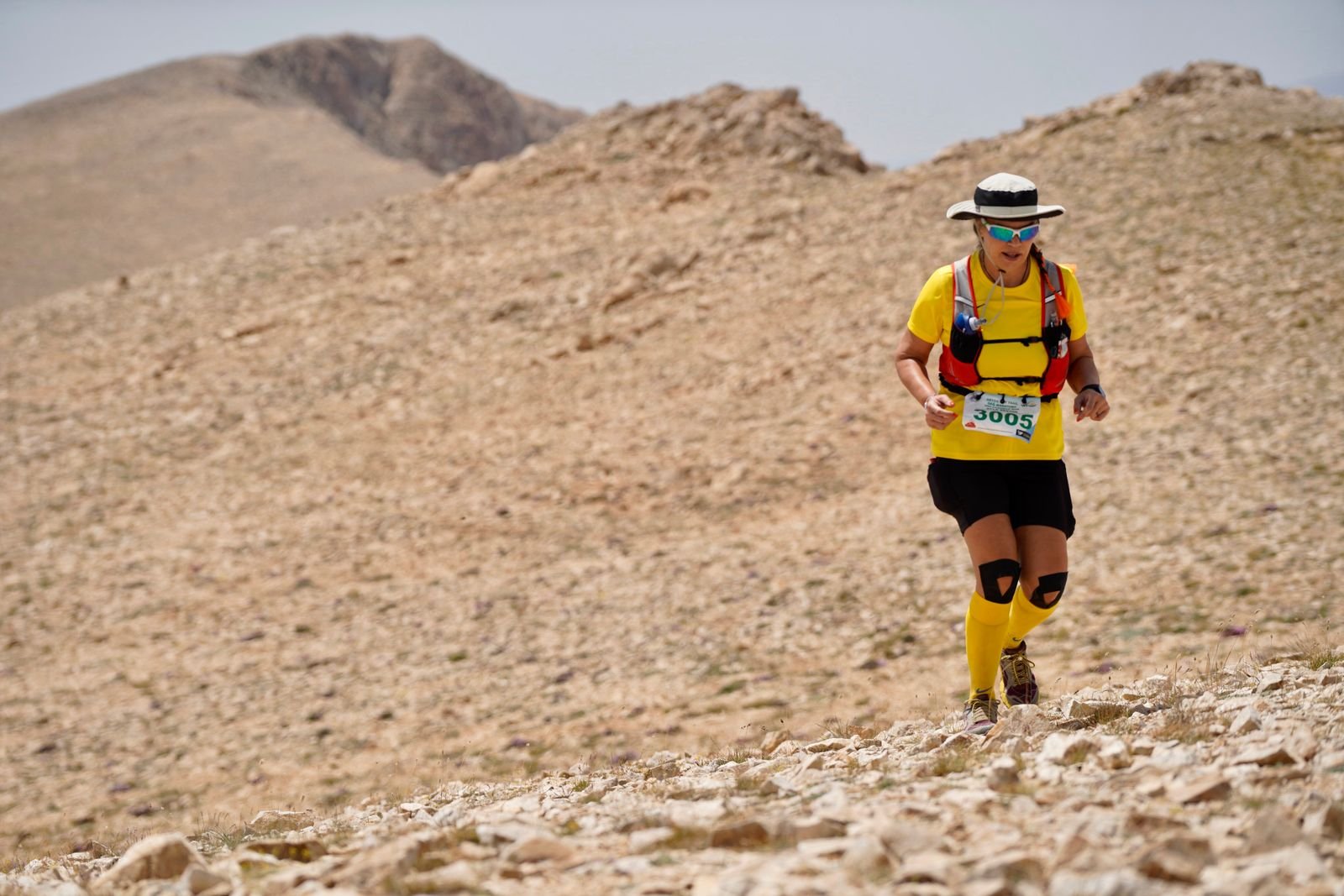 Traileuse équipée d'un gilet de trail progressant sur un terrain de montagne accidenté