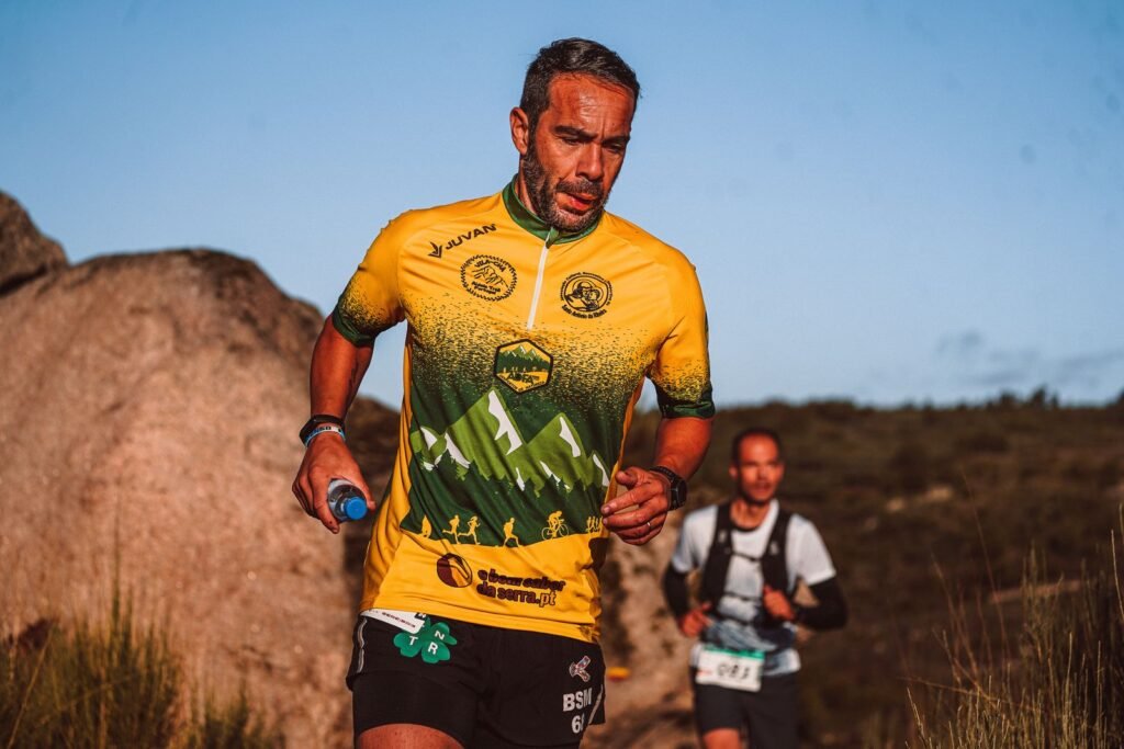Coureur de trail tenant une flasque souple sur un sentier de montagne ensoleillé