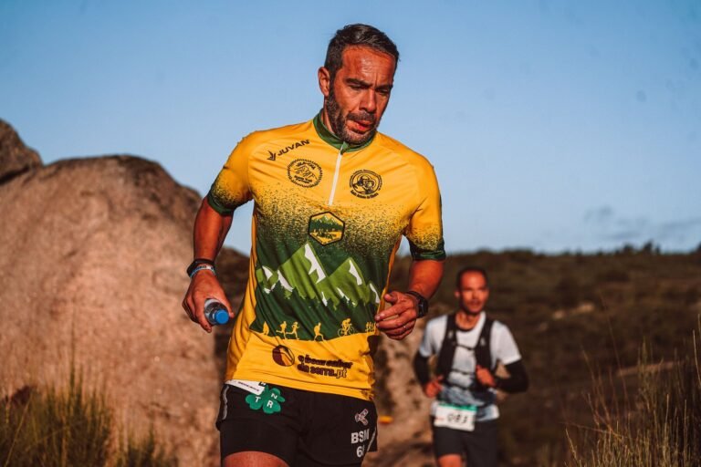 Coureur de trail tenant une flasque souple sur un sentier de montagne ensoleillé