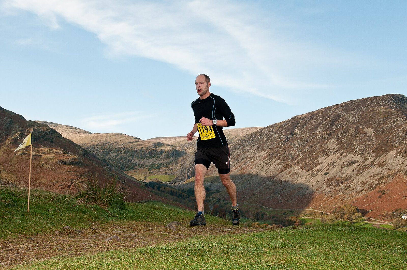 Coureur de trail sur un terrain de montagne d&eacute;couvert et expos&eacute; au vent