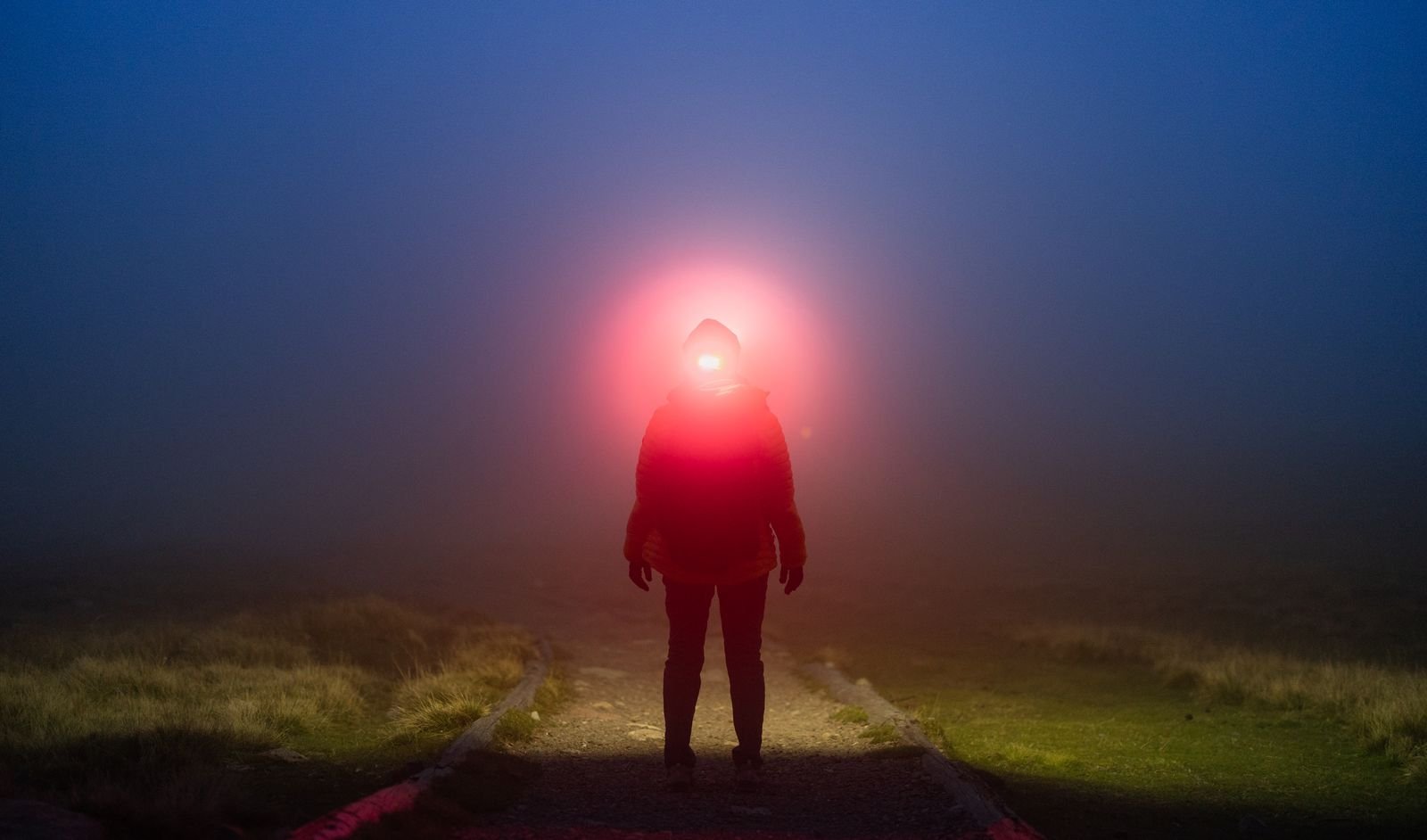 Faisceau de lampe frontale dans le brouillard nocturne sur un chemin de montagne