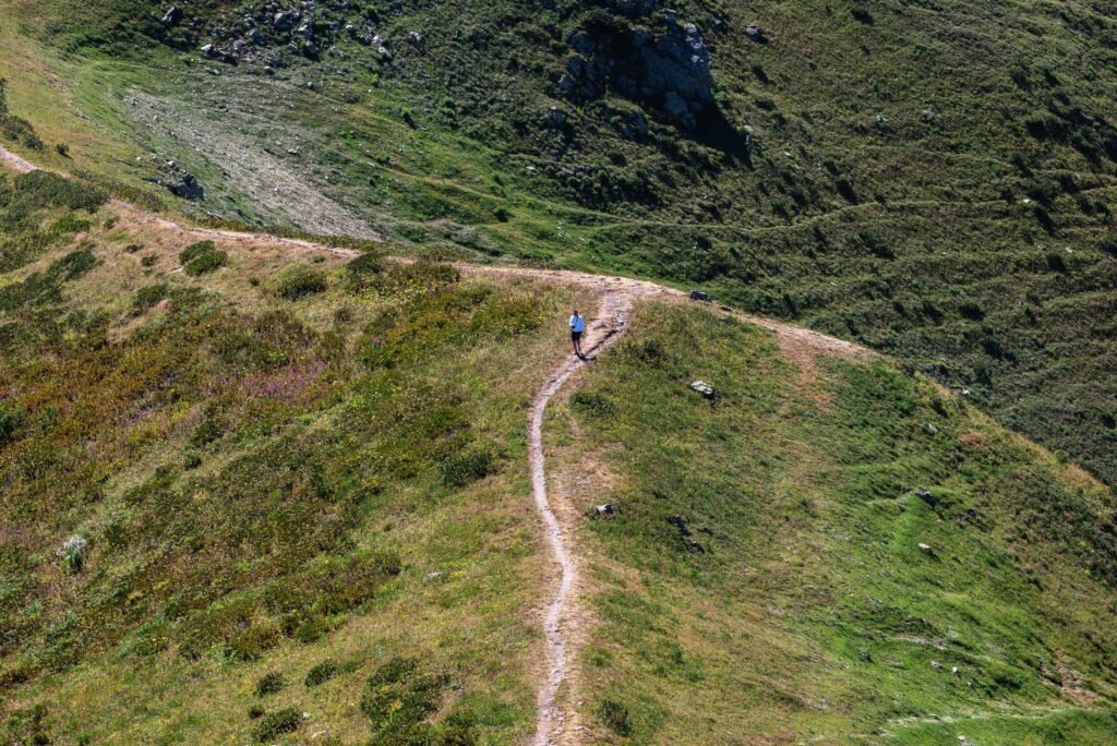 Coureur seul sur un sentier de montagne vu de haut, sans autre personne visible aux alentours